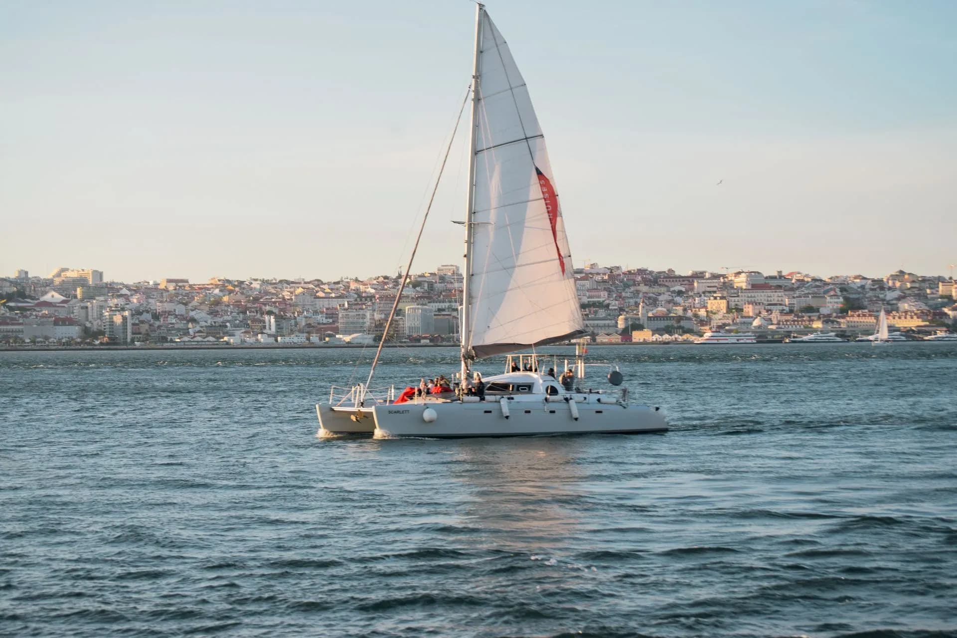A white sailing yacht on the Tagus River passing the Monument to the Discoveries in Belém, Lisbon