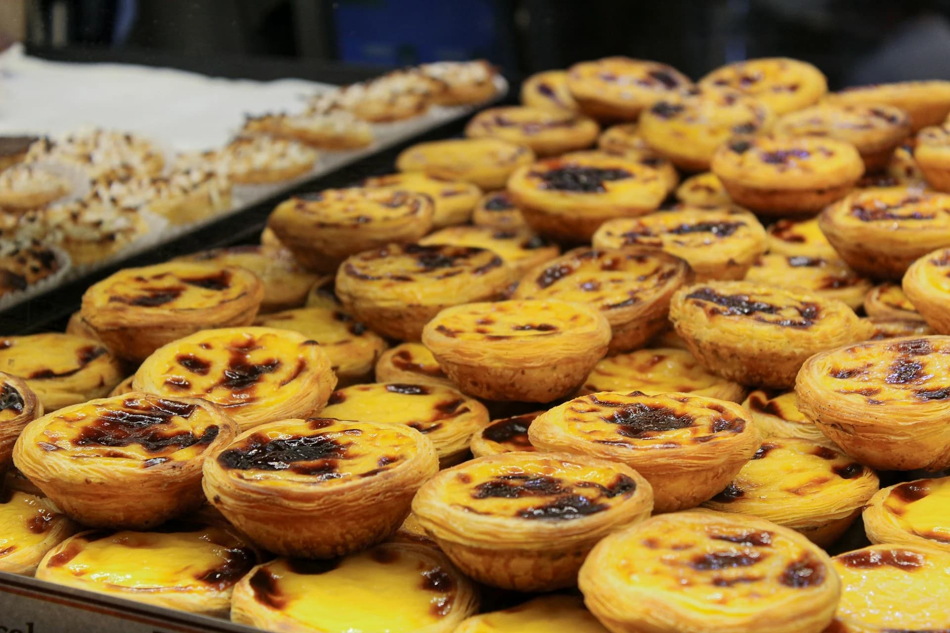 Pastéis de nata, bifana and a glass of vinho verde on a marble counter at a traditional Lisbon tasca