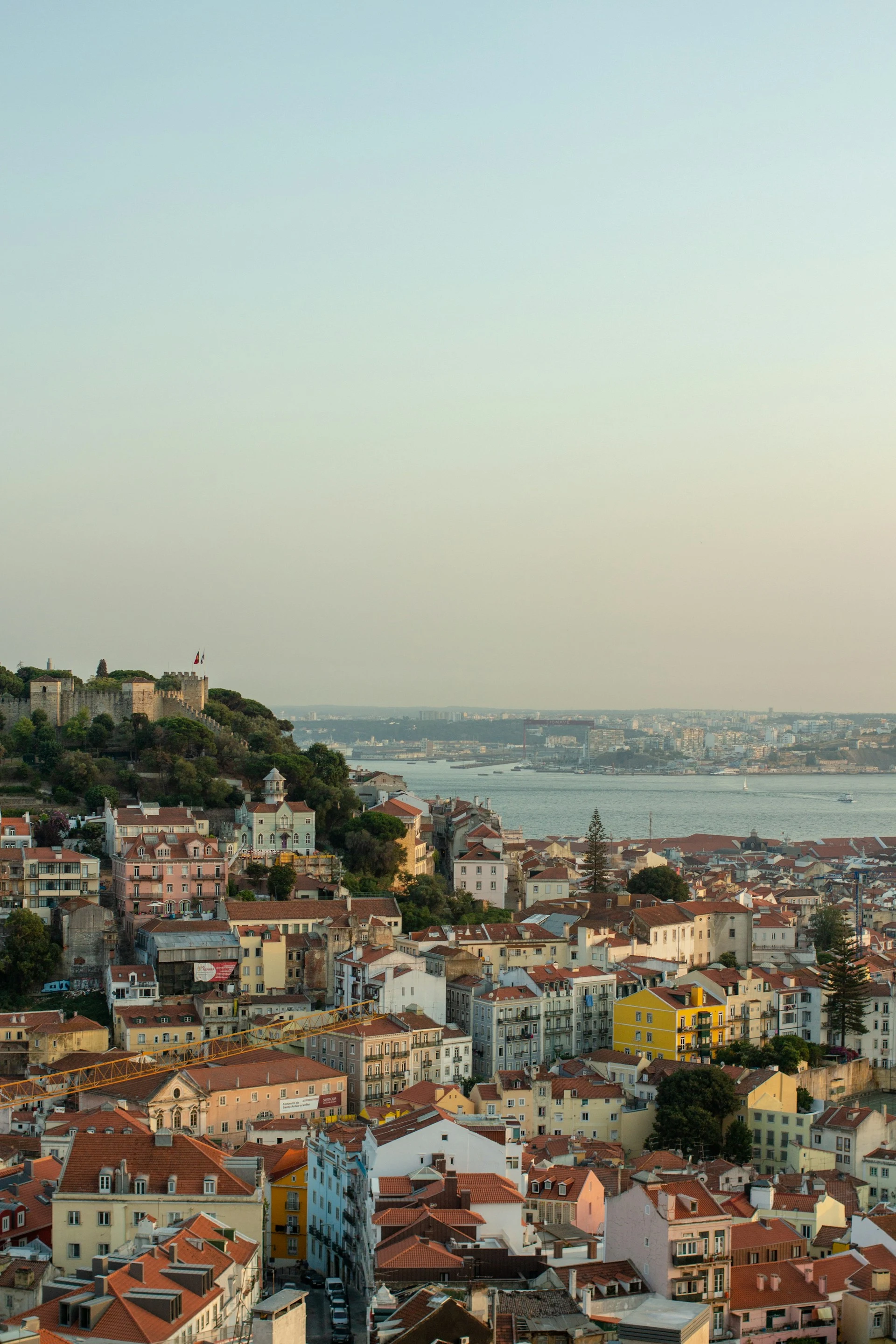 Lisbon's terracotta rooftops falling away below a hilltop viewpoint on a clear summer day