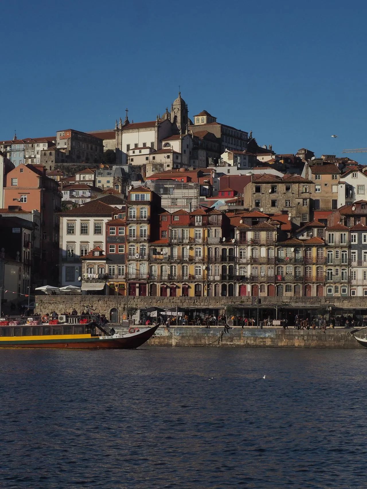 Porto's Ribeira waterfront, with colourful historic houses rising above rabelo boats moored on the Douro